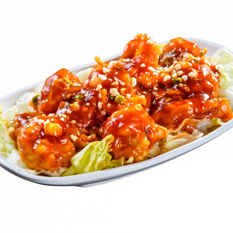 Sweet and sour shrimp with peanuts and green onions on a bed of lettuce.