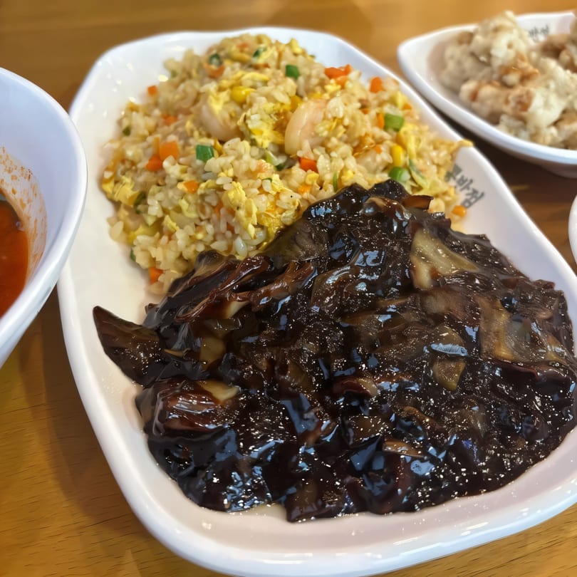 Paik's Noodle Cypress's shrimp fried rice with black bean sauce and mushrooms on a white plate.