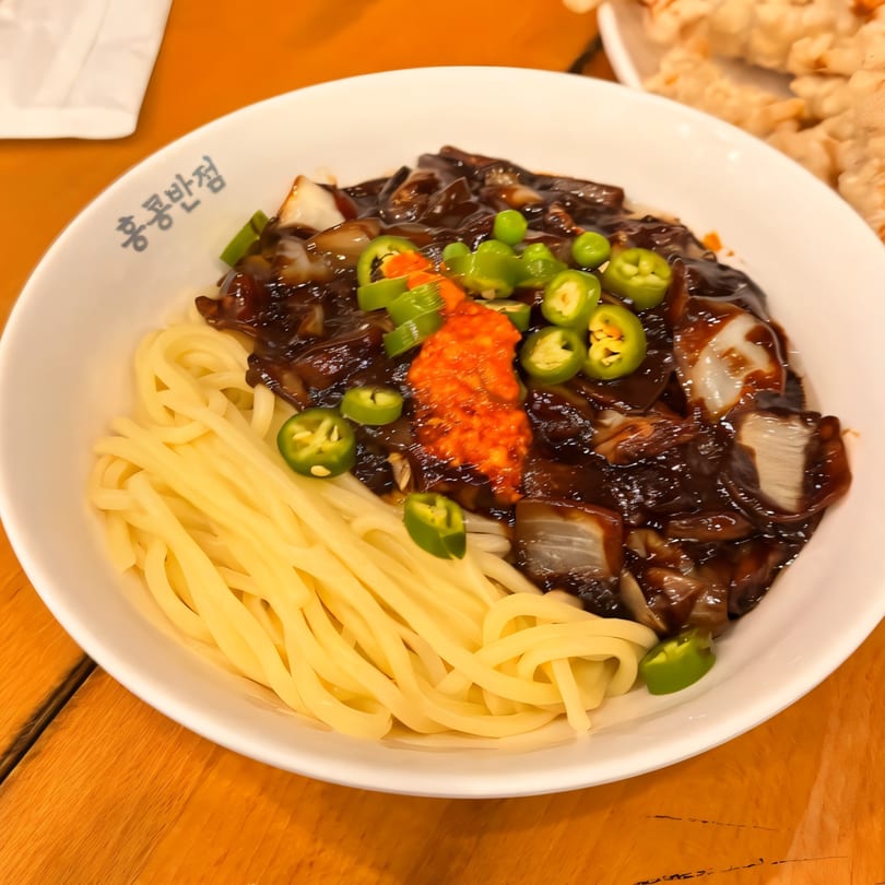 Paik's Noodle Cypress's Jajangmyeon, featuring thick noodles, black bean sauce, and green chili peppers.